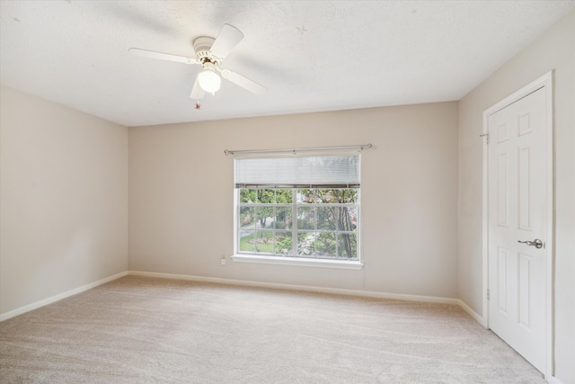 unfurnished bedroom featuring ceiling fan, light colored carpet, and a textured ceiling