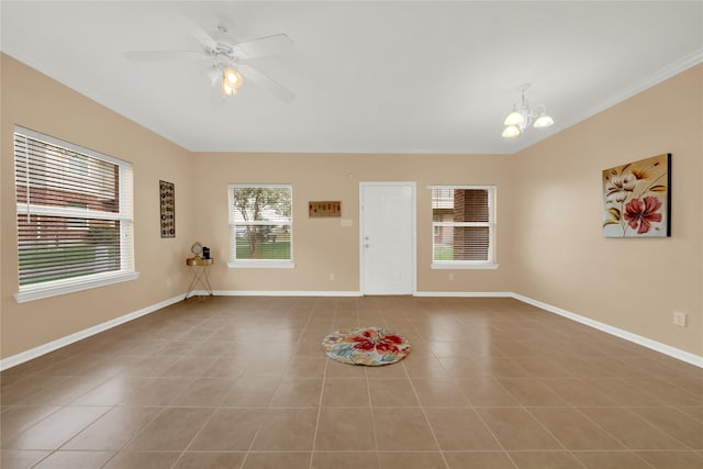 tiled empty room featuring ceiling fan with notable chandelier and crown molding