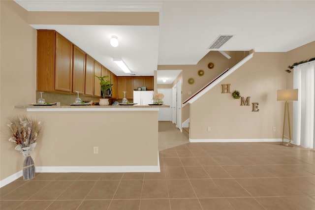 kitchen with kitchen peninsula, white fridge, light tile patterned floors, and ornamental molding