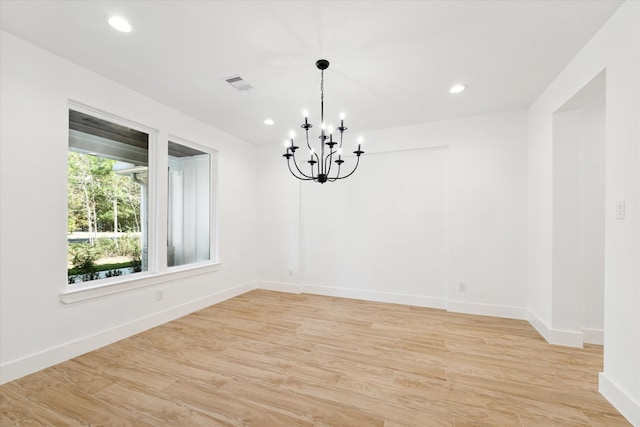 unfurnished room featuring an inviting chandelier and light wood-type flooring