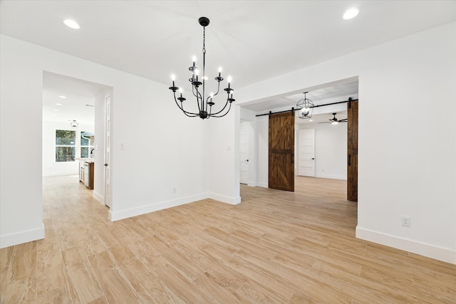 unfurnished dining area with light wood-type flooring, a barn door, and a notable chandelier