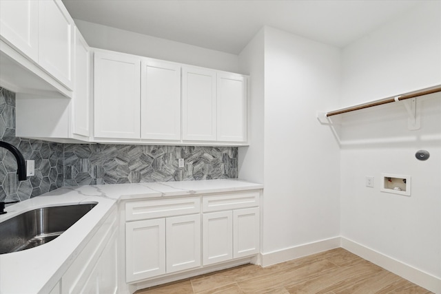 clothes washing area with cabinets, sink, washer hookup, and light hardwood / wood-style flooring