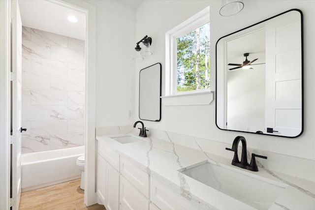 full bathroom with vanity, tiled shower / bath combo, ceiling fan, hardwood / wood-style flooring, and toilet