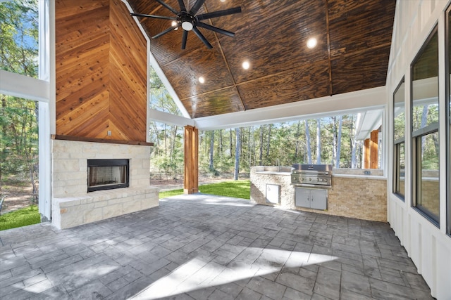 view of patio / terrace featuring an outdoor stone fireplace, ceiling fan, grilling area, and an outdoor kitchen