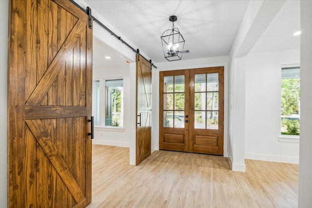 entryway featuring a barn door, light hardwood / wood-style flooring, a wealth of natural light, and french doors