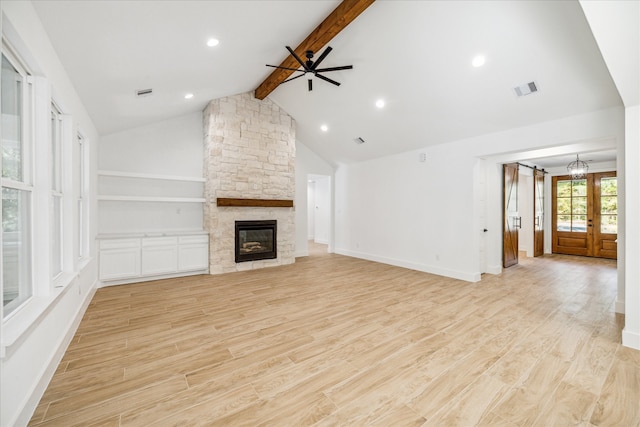 unfurnished living room with a fireplace, french doors, lofted ceiling with beams, and light hardwood / wood-style floors