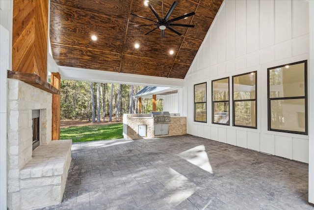 view of patio featuring grilling area, ceiling fan, an outdoor kitchen, and an outdoor stone fireplace