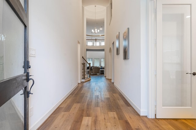 corridor featuring a notable chandelier, a high ceiling, and light hardwood / wood-style flooring