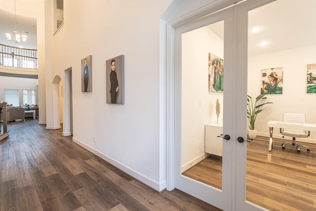 corridor featuring dark hardwood / wood-style floors, a high ceiling, a chandelier, and french doors