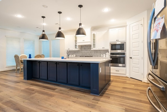 kitchen with light hardwood / wood-style floors, white cabinetry, appliances with stainless steel finishes, and tasteful backsplash