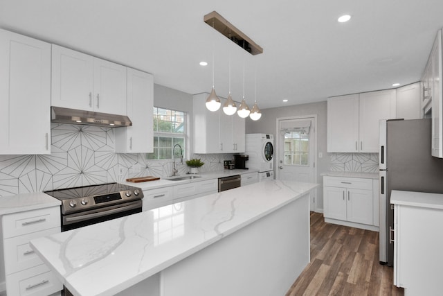 kitchen featuring decorative backsplash, sink, a kitchen island, and appliances with stainless steel finishes