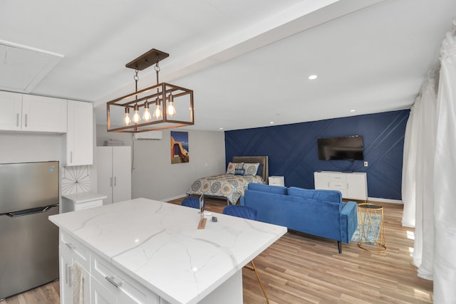 kitchen with a center island, light hardwood / wood-style flooring, decorative light fixtures, white cabinetry, and stainless steel refrigerator