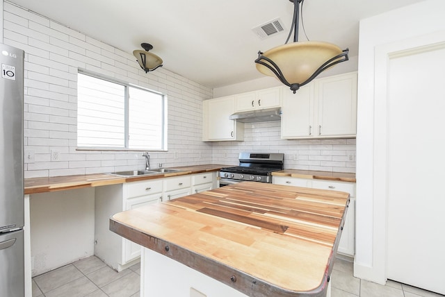 kitchen featuring butcher block counters, white cabinetry, sink, pendant lighting, and appliances with stainless steel finishes