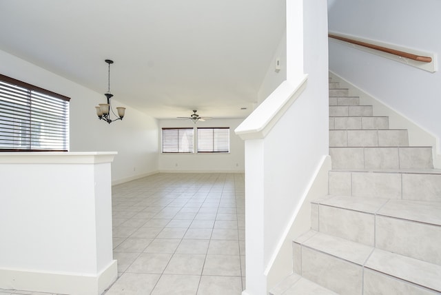 stairway featuring plenty of natural light, ceiling fan with notable chandelier, and tile patterned flooring