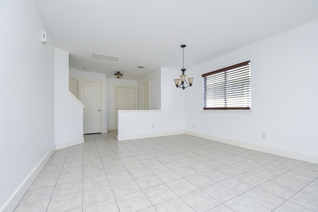 tiled spare room with a chandelier