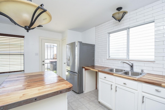 kitchen featuring butcher block counters, stainless steel fridge, and white cabinets