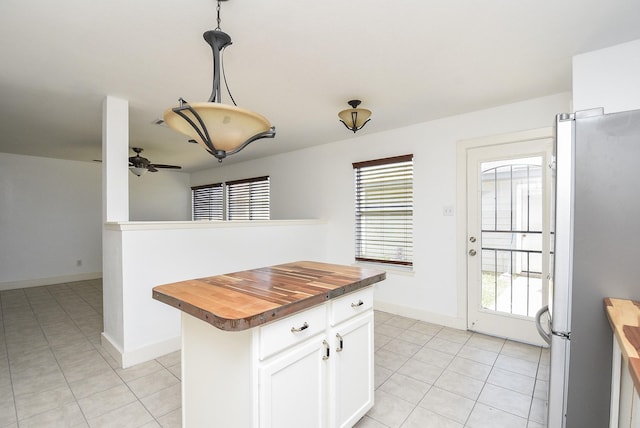 kitchen featuring wooden counters, white cabinets, hanging light fixtures, ceiling fan, and stainless steel fridge