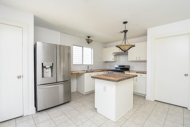 kitchen with stainless steel appliances, a kitchen island, decorative light fixtures, butcher block countertops, and white cabinetry