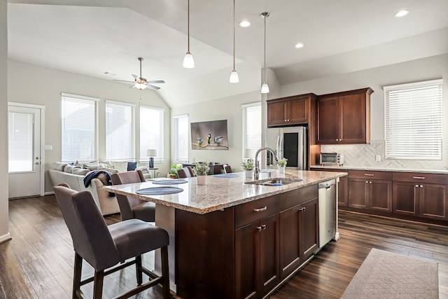 kitchen with sink, vaulted ceiling, dark hardwood / wood-style floors, appliances with stainless steel finishes, and light stone counters