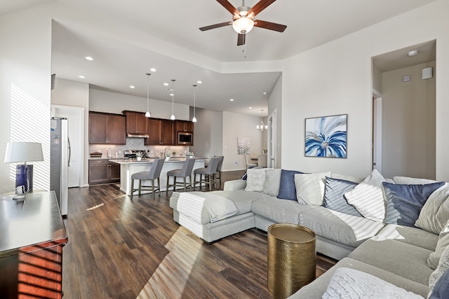 living room with ceiling fan with notable chandelier, dark hardwood / wood-style flooring, and sink