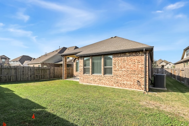 rear view of property with central air condition unit and a yard