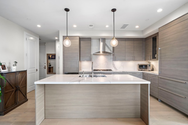 kitchen with sink, wall chimney exhaust hood, pendant lighting, and light hardwood / wood-style flooring