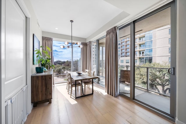 dining space with a notable chandelier, light wood-type flooring, and a wealth of natural light