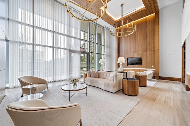 living room with expansive windows, light hardwood / wood-style flooring, a towering ceiling, a notable chandelier, and wood ceiling