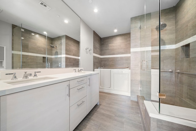 bathroom featuring vanity, a shower with door, and tile walls