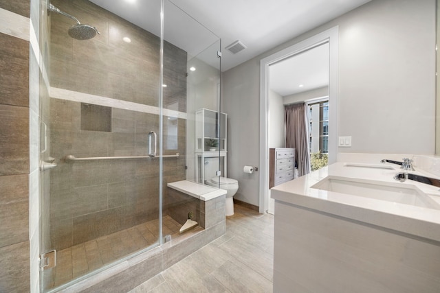 bathroom featuring tile patterned floors, vanity, toilet, and a shower with shower door