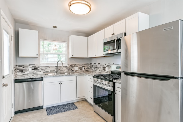 kitchen with sink, tasteful backsplash, light stone counters, white cabinetry, and stainless steel appliances