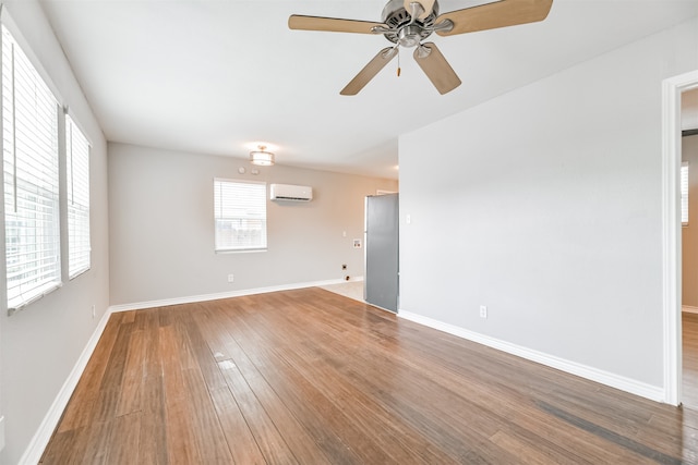 spare room with a wall unit AC, ceiling fan, and hardwood / wood-style flooring