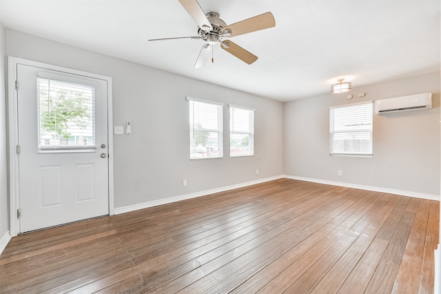 interior space featuring an AC wall unit, ceiling fan, and wood-type flooring