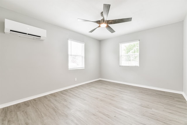 spare room with ceiling fan, a wall mounted air conditioner, and light wood-type flooring