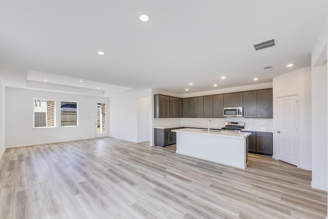 kitchen featuring visible vents, backsplash, open floor plan, appliances with stainless steel finishes, and light countertops