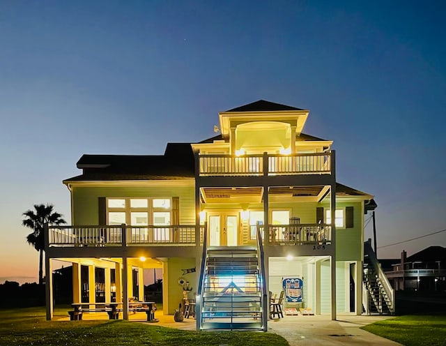 back house at dusk with a patio and a balcony