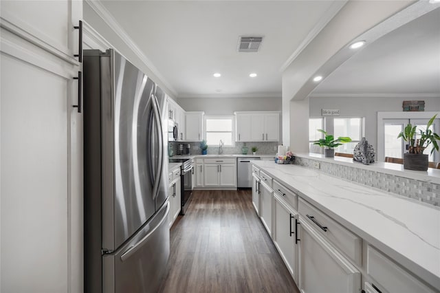 kitchen featuring plenty of natural light, light stone countertops, white cabinetry, and appliances with stainless steel finishes