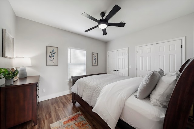 bedroom with dark hardwood / wood-style flooring, ceiling fan, and multiple closets