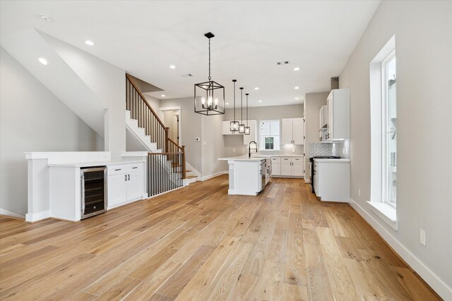 kitchen featuring white cabinets, a center island, decorative light fixtures, and wine cooler