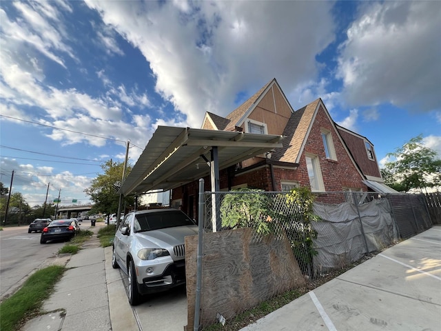 1411 Wheeler St, Houston, TX 77004 - view of side of property featuring brick siding, a shingled roof, a carport, and driveway