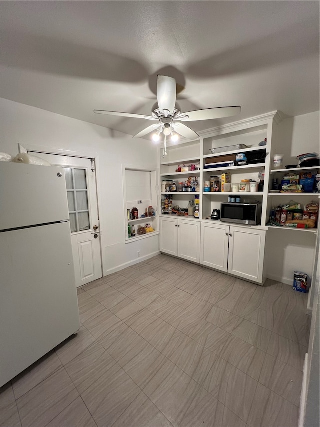 interior space with white fridge, white cabinetry, and ceiling fan