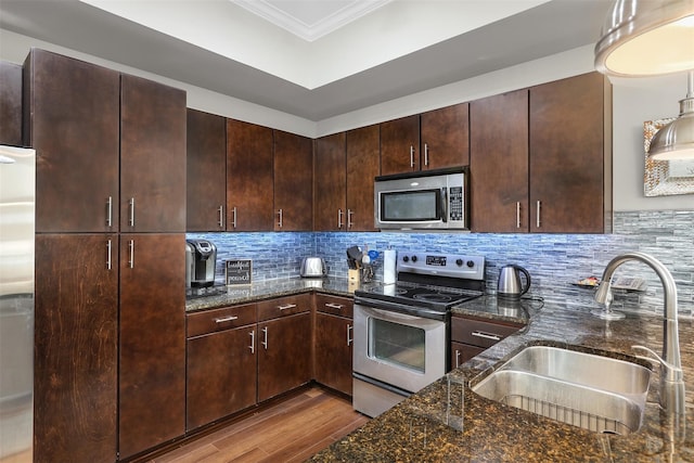 kitchen with dark stone counters, sink, light wood-type flooring, appliances with stainless steel finishes, and dark brown cabinets