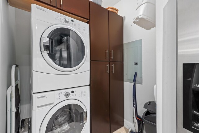 clothes washing area featuring cabinets, electric panel, and stacked washer / drying machine