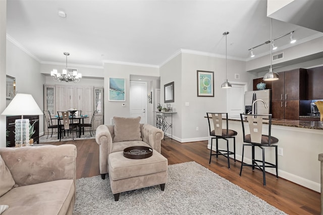 living room featuring a chandelier, sink, dark wood-type flooring, and ornamental molding