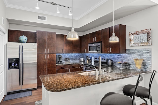 300 St Joseph Pkwy Unit 115, Houston, TX 77002 - kitchen with stainless steel appliances, a peninsula, wood finished floors, rail lighting, and dark stone countertops