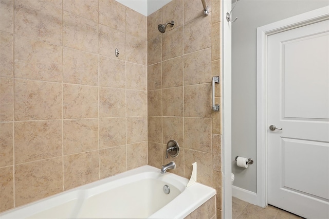 bathroom featuring tile patterned flooring, tiled shower / bath combo, and toilet