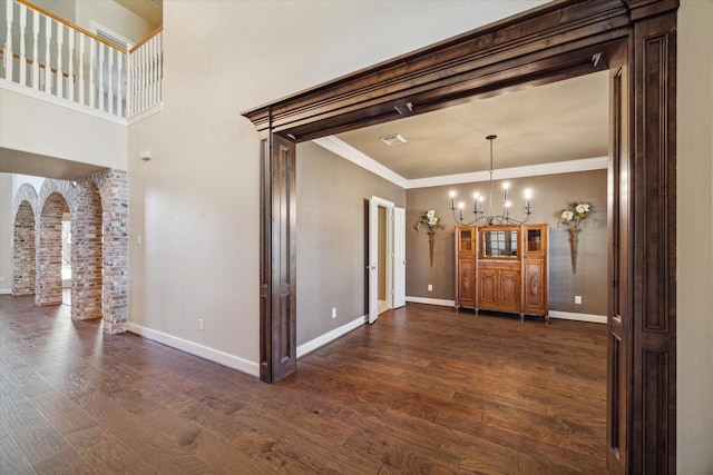 interior space featuring a notable chandelier, ornamental molding, and dark wood-type flooring