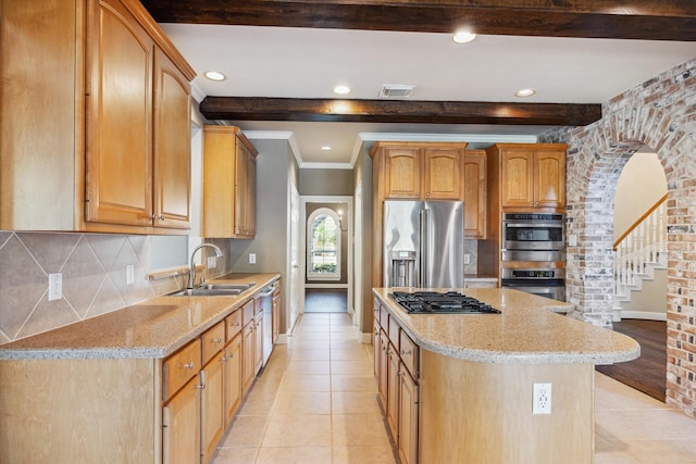 kitchen featuring a kitchen island, light stone countertops, sink, and appliances with stainless steel finishes