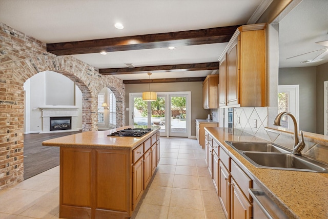 kitchen with stainless steel appliances, sink, light tile patterned floors, pendant lighting, and a kitchen island