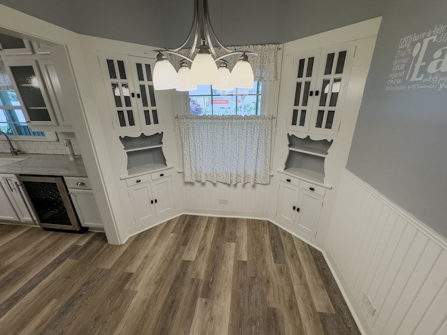 dining space with wine cooler, sink, dark hardwood / wood-style flooring, and an inviting chandelier